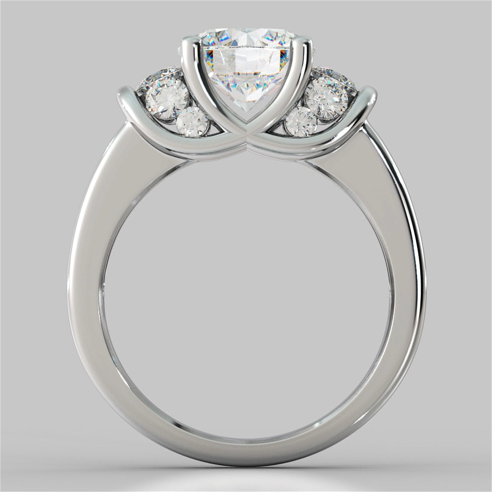 Silver ring with a heart-shaped center stone and round side stones on a gray background