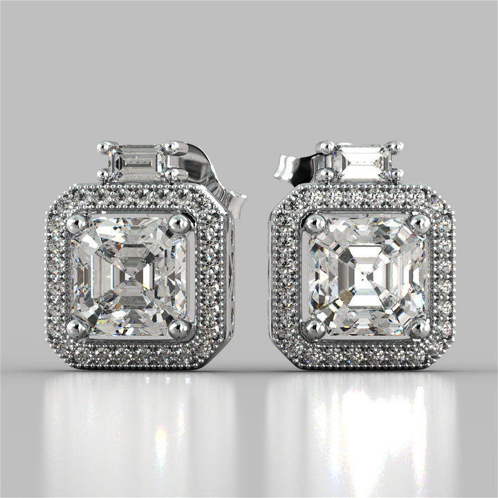 Pair of diamond earrings on a reflective surface with a light gray background