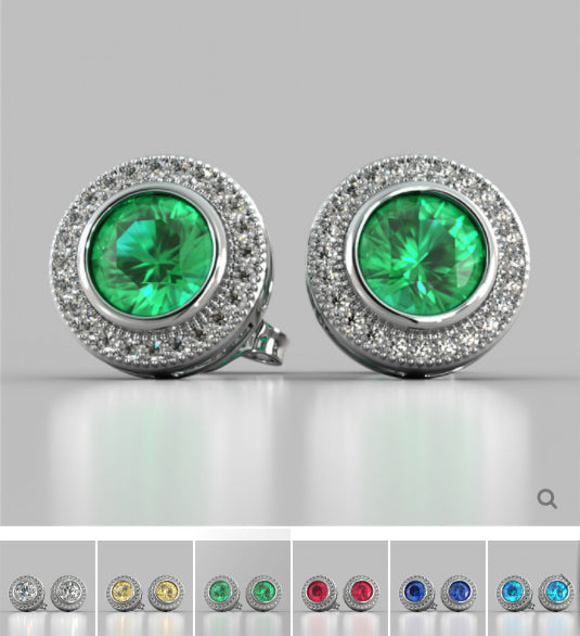 Pair of earrings with green gemstones and silver settings on a gray background.