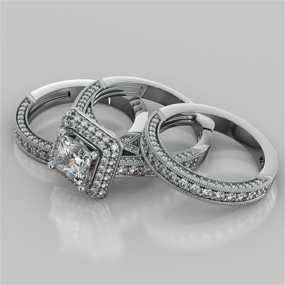 Three silver rings with diamond accents on a light gray background